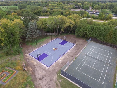 Outdoor residential sports area with a gray and purple basketball court and Minnesota Vikings central logo.