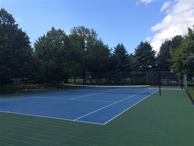  Outdoor residential sports court with a blue and green surface, featuring a tennis net.