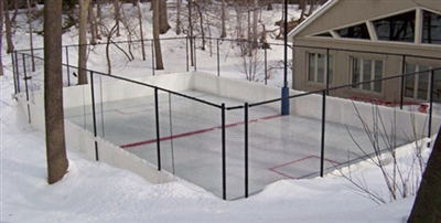 An outdoor ice hockey rink surrounded by a black fence.