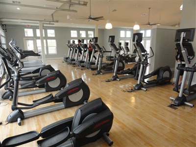 Indoor exercise room with wooden flooring and multiple cardio machines in Marshan.