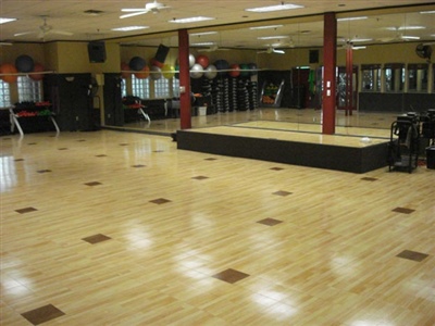 Multipurpose exercise room with wooden floors and a raised platform. 