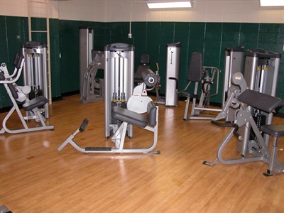 Indoor workout room with wooden flooring and multiple workout equipment.