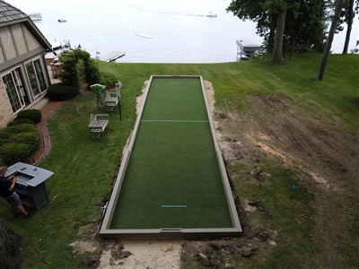 Outdoor bocce ball court with green turf and low border wall in Cedar Lake.