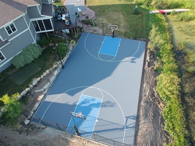 A basketball court with a blue and grey surface with white lines.