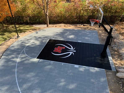 A basketball court with a grey and black surface, white lines, and a sport court logo in the center.