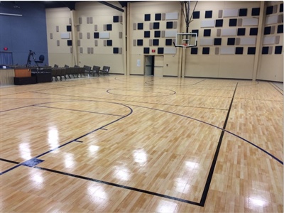 An indoor basketball court with a polished wood surface, black lines, and a modern wall design featuring square patterns in Savage.