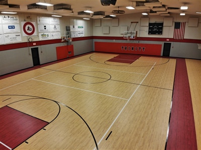 An indoor basketball court with a light wood surface, black lines, red key areas, and red sidelines.