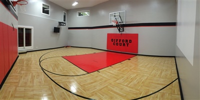  A small indoor basketball court with a polished wood surface, black lines, and grey walls, featuring a red key area in Spring Lake.