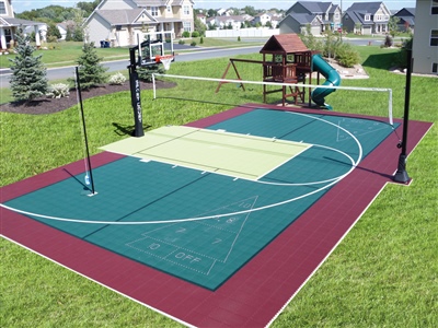  Outdoor residential sports court with a green and red surface, a basketball hoop, and a volleyball net, with a playground set in the background.