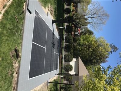 Outdoor residential sports court with a gray and black surface, a basketball hoop, and a tennis net in Victoria.