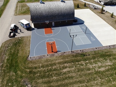 Outdoor residential sports area with a gray and orange basketball court and a tennis court in Lake Elmo.